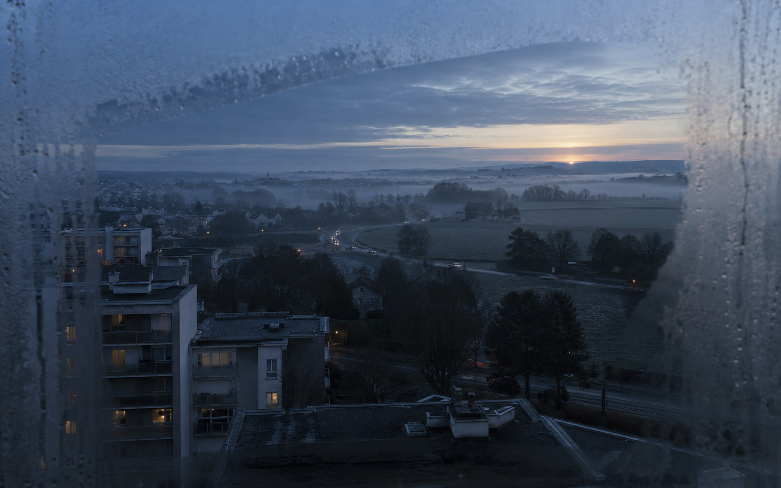 La lisière d’une ville française à l’aube, vue d’une fenêtre